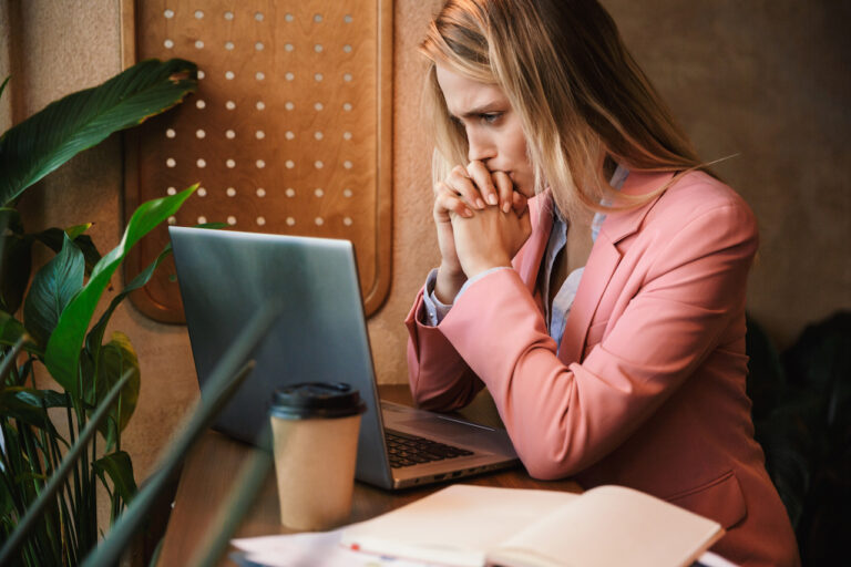 Attractive worried young businesswoman looking at laptop computer
