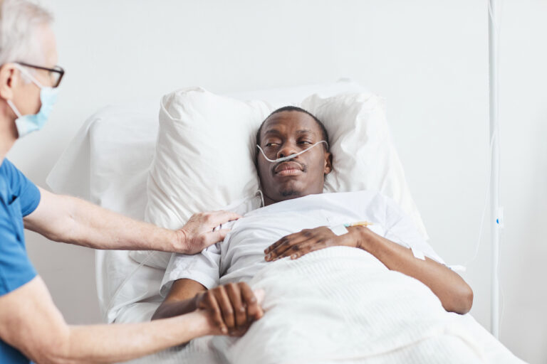 man lying in a hospital bed being nursed